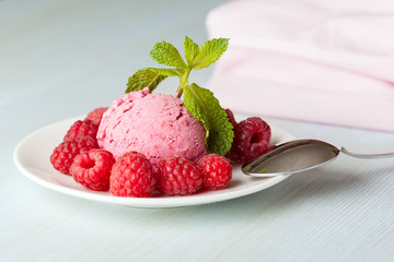 A raspberry ice cream with berries and mint leaves on a light background