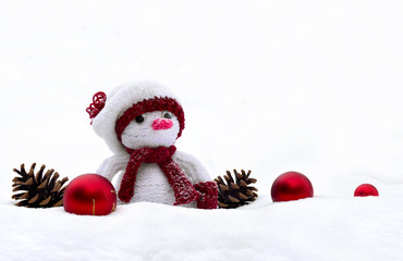 Snowman knitted handmade, pine cones, christmas red balls on snow with space for text. Christmas decoration