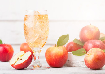 Glass of homemade organic apple cider with fresh apples in box on wooden background with sun light