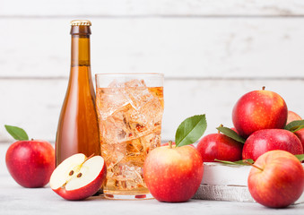 Bottle and glass of homemade organic apple cider with fresh apples in box on wooden background