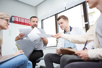 Students passing over papers with their ideas to teacher at the end of seminar or discussion