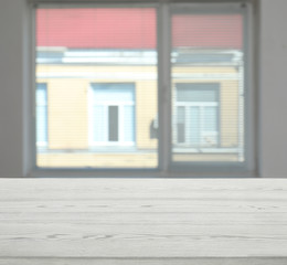 Fototapeta premium Wooden table in front of window with shutters indoors