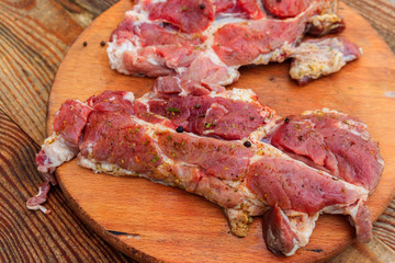 Fresh raw pork meat with spices on wooden cutting board on rustic table