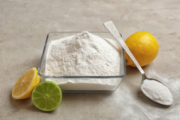 Bowl and spoon of baking soda with lemons on gray table
