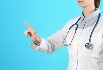 Female doctor pointing on color background, closeup