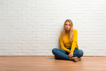 Young girl sitting on the floor with sad and depressed expression. Serious gesture