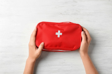Woman holding first aid kit on wooden background, top view - obrazy, fototapety, plakaty