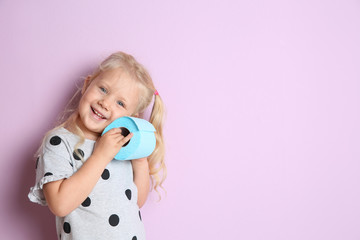 Cute little girl holding toilet paper roll on color background. Space for text