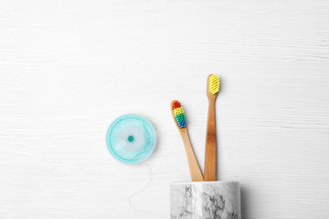 Flat lay composition with bamboo toothbrushes on white wooden background