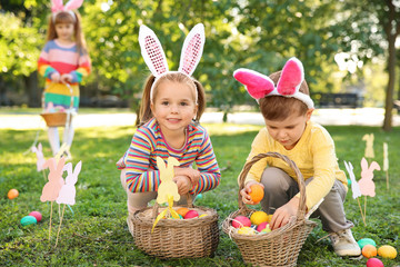 Cute little children hunting eggs in park. Easter tradition