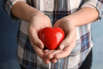 Woman holding red heart in hands, closeup. Helping and supporting concept