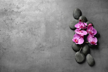 Fototapeta na wymiar Flat lay composition with spa stones and orchid flowers on grey background. Space for text