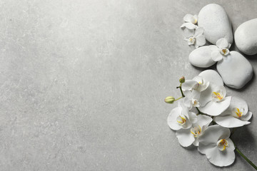 Flat lay composition with spa stones and orchid flowers on grey background. Space for text