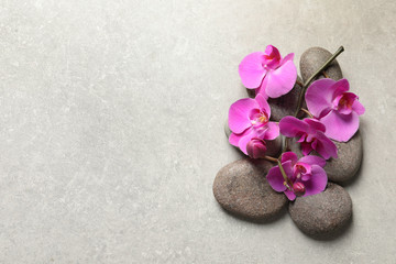 Fototapeta na wymiar Flat lay composition with spa stones and orchid flowers on grey background. Space for text