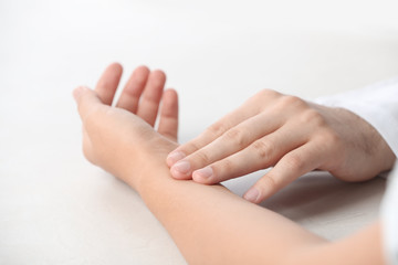 Doctor checking patient's pulse on table, closeup