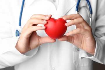 Doctor holding toy heart, closeup. Pulse checking