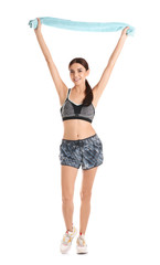 Beautiful young woman in sportswear with towel on white background