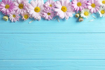 Naklejka na ściany i meble Beautiful chamomile flowers on wooden background, flat lay with space for text