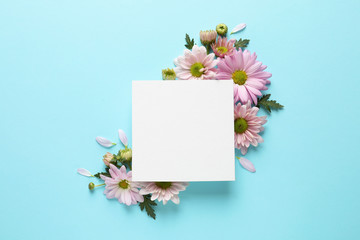 Beautiful chamomile flowers and paper card on color background, flat lay with space for text