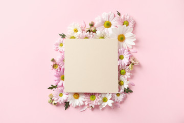 Beautiful chamomile flowers and paper card on color background, flat lay with space for text