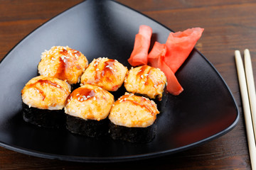 Set sushi on a black triangular plate with ginger closeup. Photo of japanese food on dark wooden background.