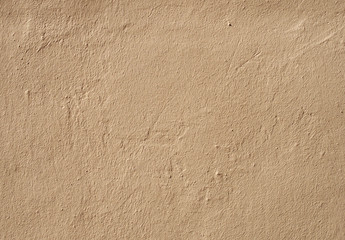 a beige brown rough textured grainy painted cement wall with marks and scratches