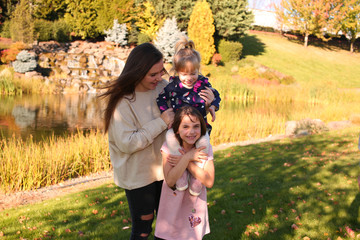 Tree beautiful sisters playing outside, in the park, golden Autumn, happy family, best friends, best sisters
