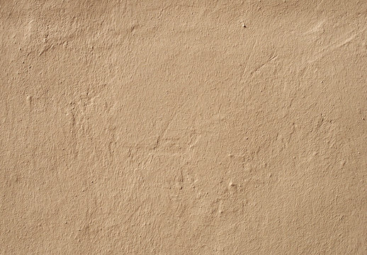 a beige brown rough textured grainy painted cement wall with marks and scratches