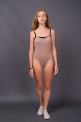 Young beautiful woman with blond hair wearing leotard against gr