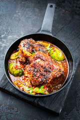 Traditional barbecue leg of lamb with lemon and tomatoes as closeup in a cast-iron skillet