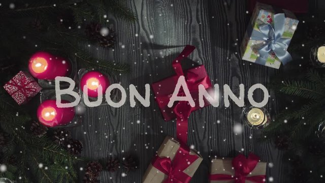 Animation Buon Anno - Happy New Year in italian, white letters and red candles, falling snow. Top view