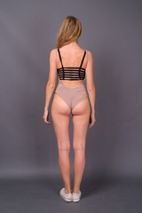 Young beautiful woman with blond hair wearing leotard against gr