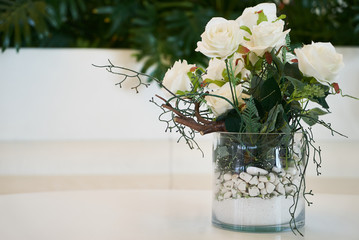 Decorative white roses in a glass vase, close-up.