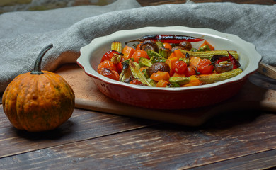 Pumpkin and a plate of grilled vegetables on a wooden background. Copy Space.