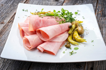 Traditioneller deutscher Kochschinken geschnitten aufgerollt und dekoriert mit Peperoni und Oliven...