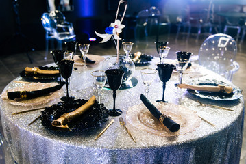 Tables set for an event party or wedding reception. luxury elegant table setting dinner in a restaurant. Black and gold glasses and dishes.