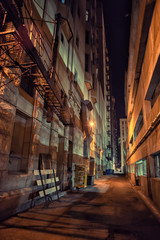 Dark and eerie downtown urban city alley with a fire escape next
