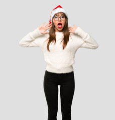 Girl with celebrating the christmas holidays surprised and shocked. Expressive facial emotion on isolated grey background