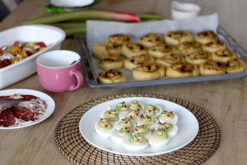 Table with savory pesto rolls, deviled eggs, sweet potato salad, pepperoni and yogurt sauce. Selective focus.