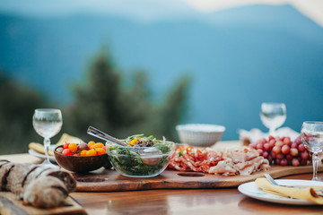 Salami platter and salad on a wooden table in the garden