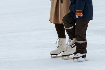 Mom teaches little son to ice skate. Unknowns boy with his mother ride on the ice rink