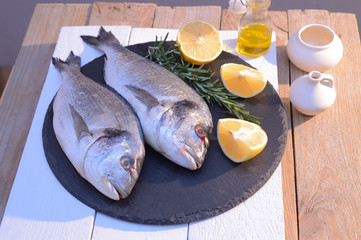 dorado fish on a black plate with lemon, rosemary