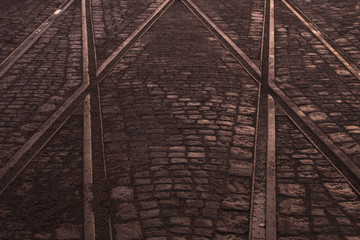 Crossing of tram rails on stone pavement in the city abstract background