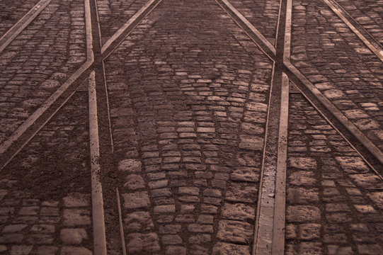 Crossing of tram rails on stone pavement in the city background