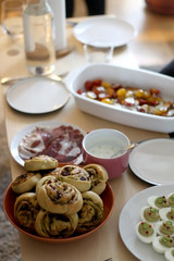 Table with savory pesto rolls, deviled eggs, sweet potato salad, pepperoni and yogurt sauce. Selective focus.
