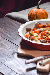 Delicious vegetables baked in the oven on a ceramic plate on a wooden table. Devices, fabric and accessories. Copy space.