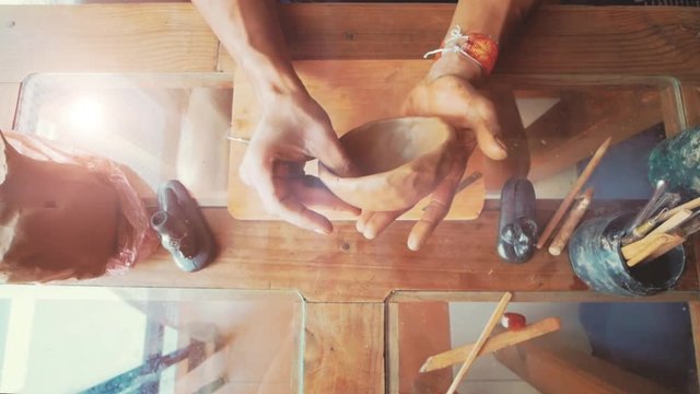 Hand's molding clay piece on a homemade workshop 