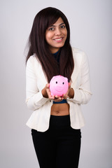 Studio shot of young happy Persian businesswoman smiling while h