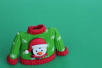 green and red resin sweater with snowflakes and a penguin on it standing on a green background with writing space