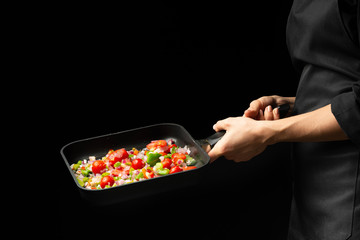 Chef preparing vegetables on a dark background on a grill pan